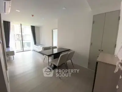 Modern open-plan living area with dining table and large windows in a bright apartment.