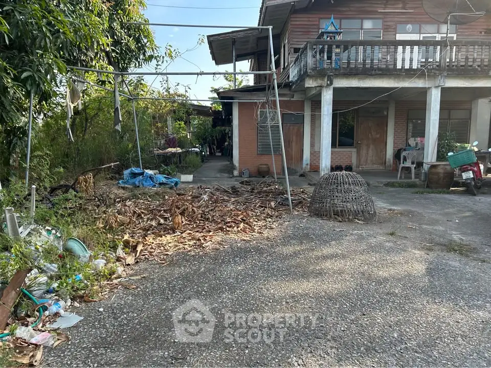 Rustic two-story house with balcony and spacious yard, ideal for renovation enthusiasts.