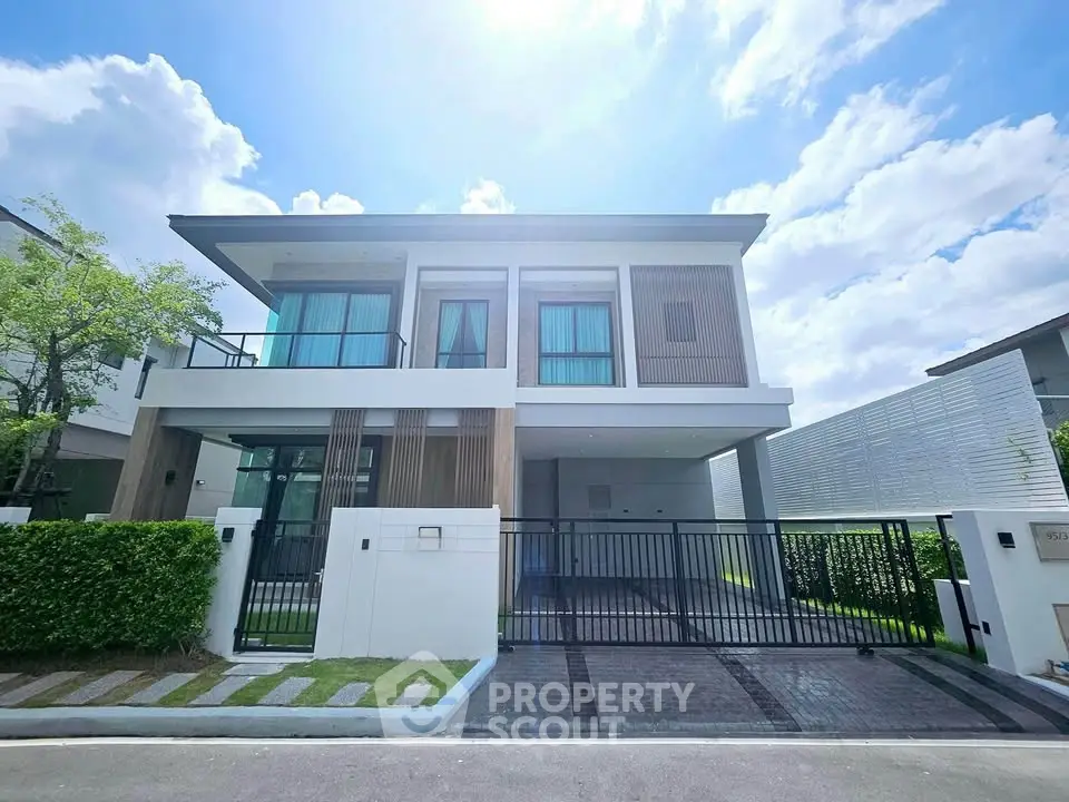 Modern two-story house with sleek design and spacious driveway under a bright blue sky.