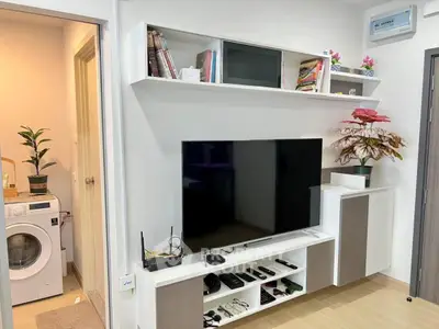 Modern living room with sleek TV setup and laundry area