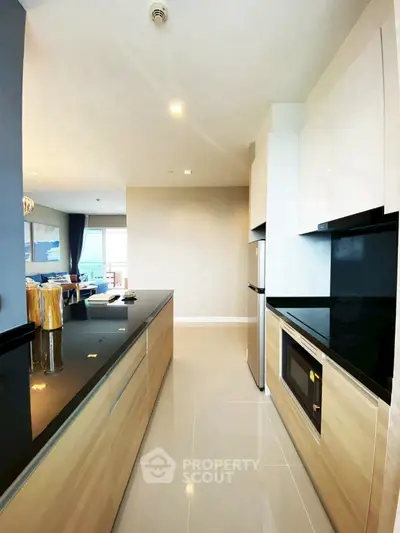 Modern kitchen with sleek black countertops and built-in appliances in a stylish apartment.