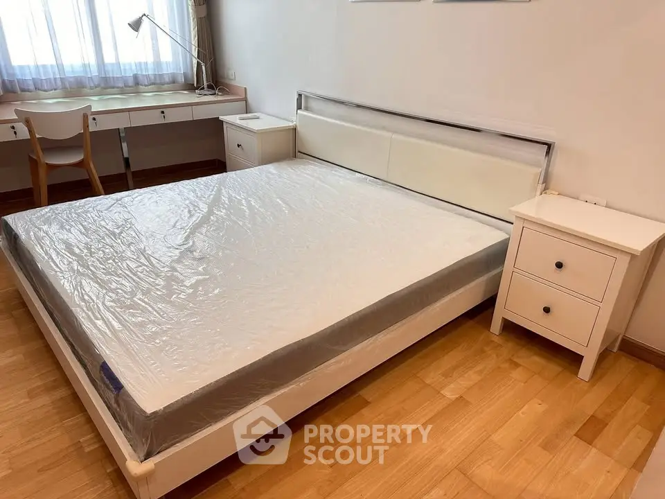 Spacious bedroom with modern furniture and natural light, featuring a large bed and work desk.