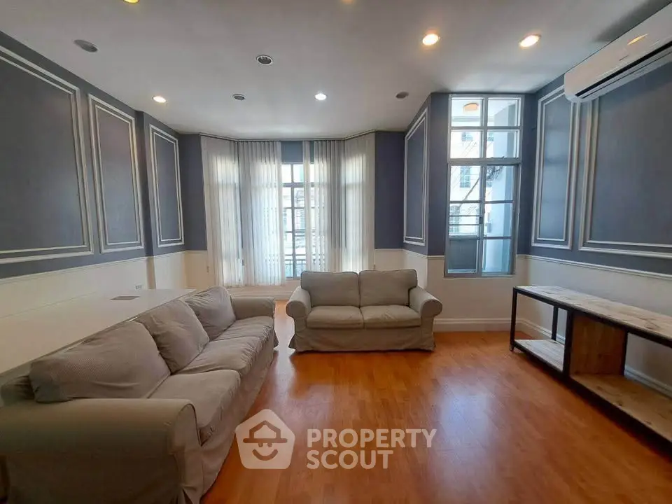 Spacious living room with elegant decor and natural light, featuring cozy sofas and hardwood flooring.