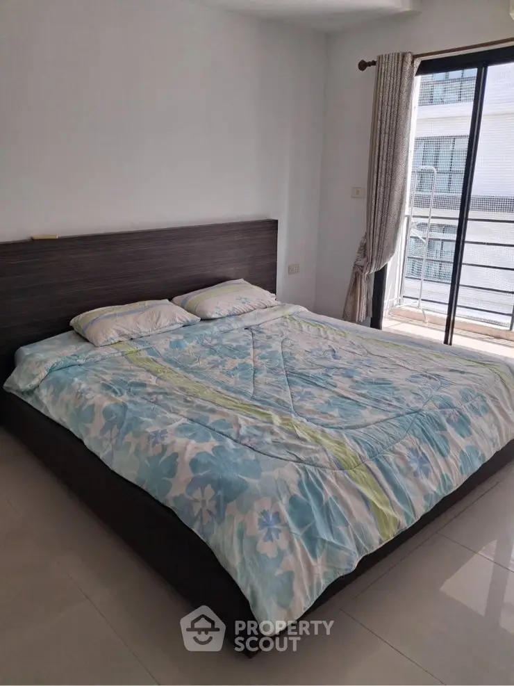 Spacious bedroom with large bed and balcony access in modern apartment