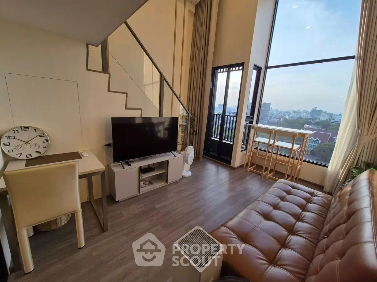 Modern living room with city view, featuring stylish furniture and large windows for natural light.