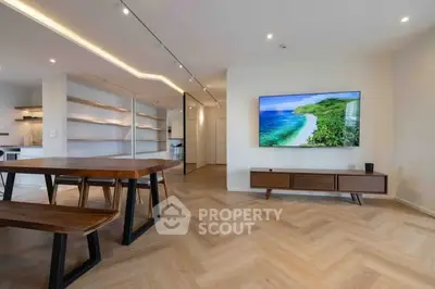 Modern living room with sleek wooden furniture and large TV, open layout design.