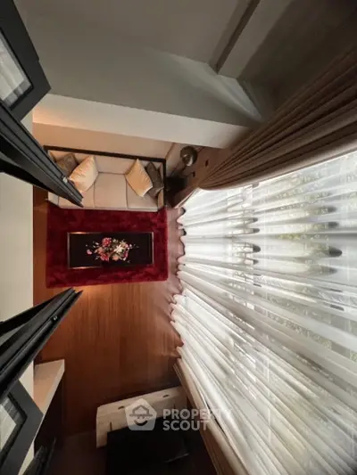 Elegant living room with cozy sofa, red rug, and floor-to-ceiling curtains for a luxurious ambiance.