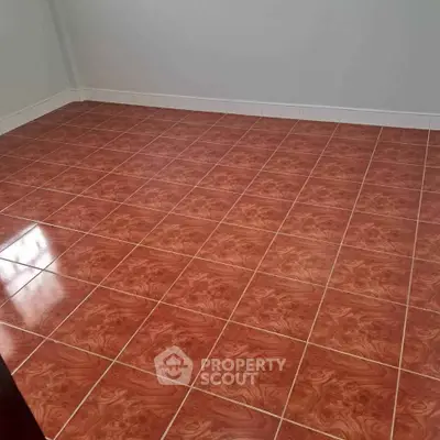 Spacious empty room with polished red tile flooring and white walls.