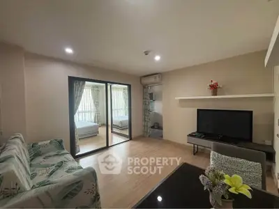 Spacious living room with modern decor and natural light, featuring a cozy seating area and large TV.