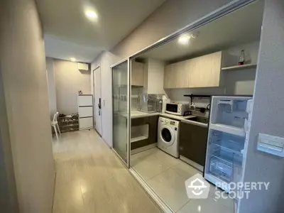 Modern kitchen with washing machine and open fridge in sleek apartment