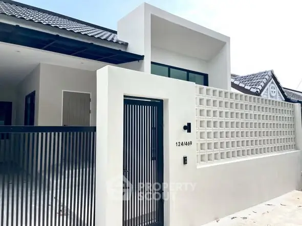 Modern minimalist house exterior with gated entrance and unique architectural design.
