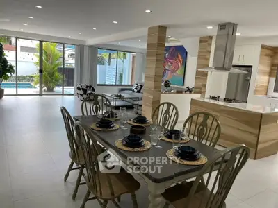 Spacious open-plan living and dining area with modern kitchen and pool view, perfect for entertaining.