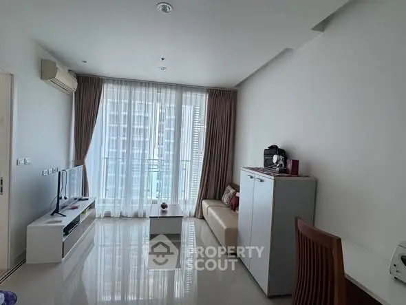 Modern living room with sleek furniture and large windows offering city views.