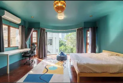 Spacious bedroom with modern decor and large windows offering natural light and garden view.