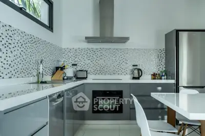 Modern kitchen with sleek gray cabinets, stainless steel appliances, and mosaic tile backsplash.