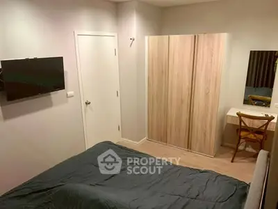 Cozy bedroom with modern furnishings and wall-mounted TV in a stylish apartment.