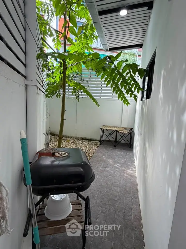 Charming outdoor space with BBQ grill and lush greenery, perfect for relaxation and entertaining.