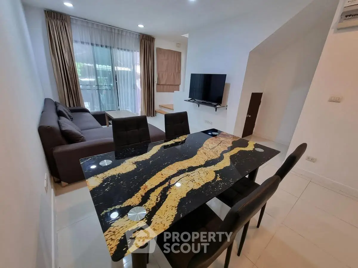 Modern living room with stylish dining area and large sofa, featuring a sleek TV setup.