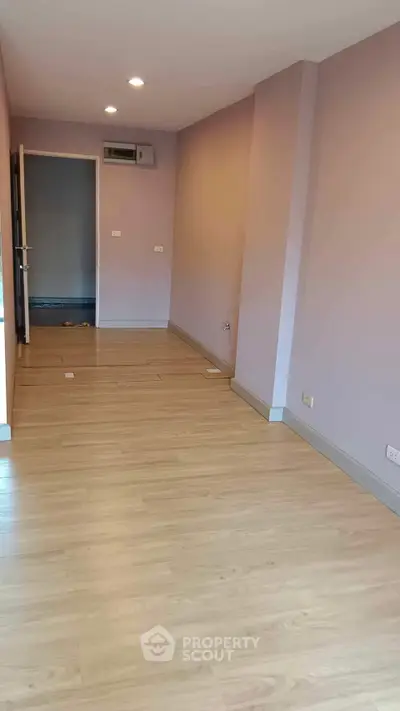 Spacious empty room with wooden flooring and recessed lighting, ideal for customization.