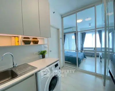 Modern apartment with sleek kitchen and cozy bedroom, featuring a washing machine and stylish decor.