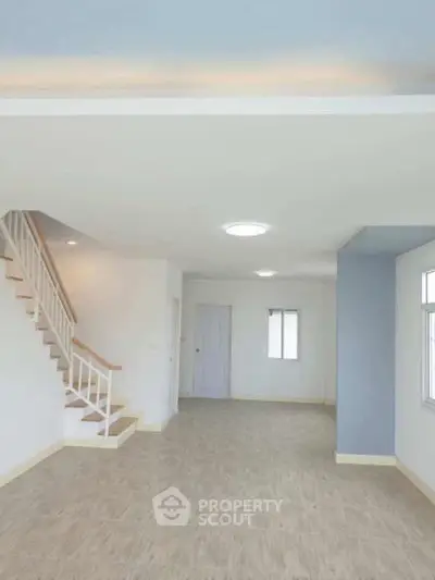Spacious open-plan living area with modern staircase and ample natural light.