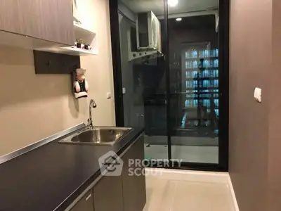 Modern kitchen with sleek cabinetry and glass sliding door to balcony.