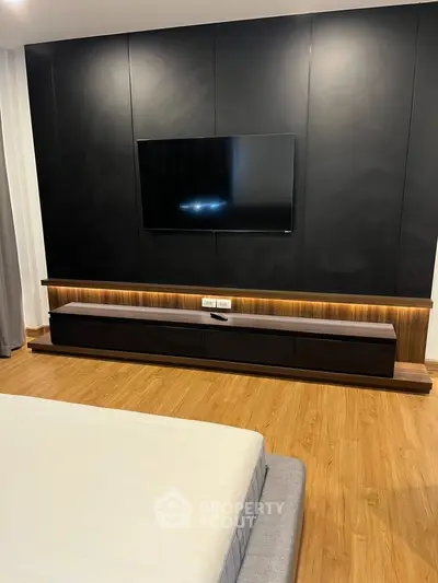 Modern bedroom with sleek TV wall unit and wooden flooring