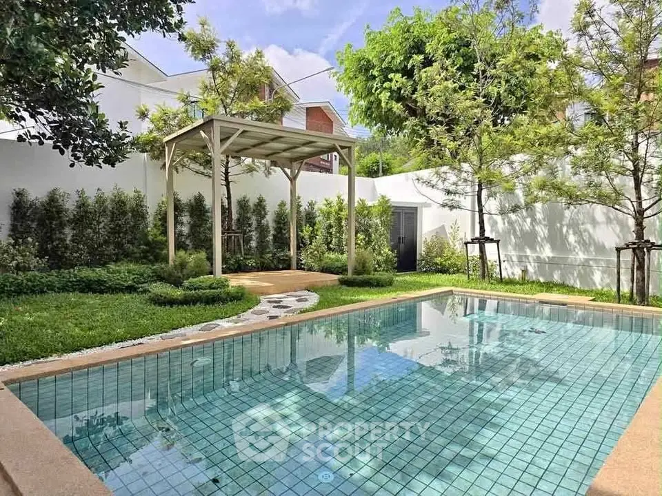 Charming backyard with a sparkling pool and lush greenery, perfect for relaxation and outdoor gatherings.