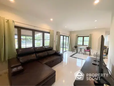 Spacious living room with modern leather sofa and large windows offering natural light