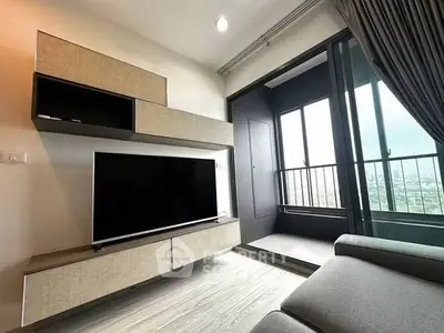 Modern living room with sleek TV unit and balcony view in high-rise apartment.