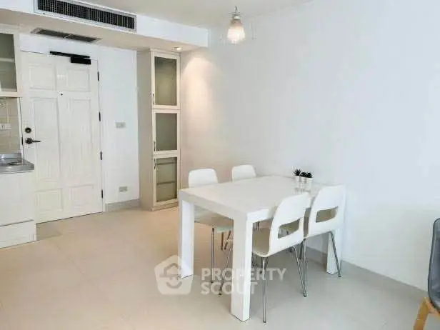 Modern minimalist dining area with white table and chairs in a bright apartment.