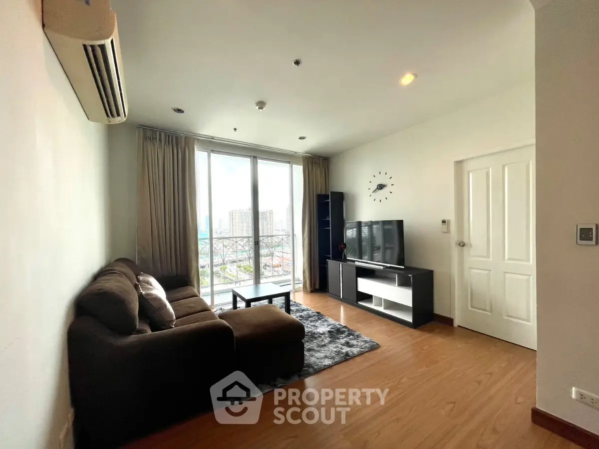 Spacious living room with modern decor and city view, featuring a cozy sofa and entertainment center.