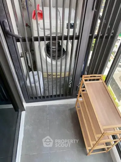 Compact balcony with washing machine and wooden shelf, ideal for urban living.