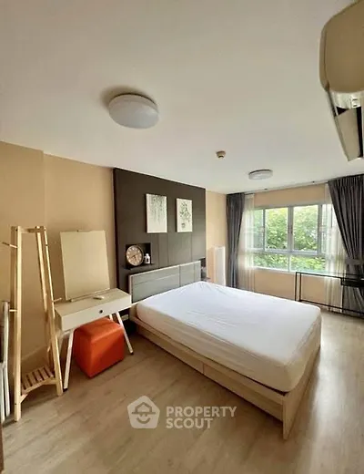 Spacious bedroom with modern decor and large window offering natural light.