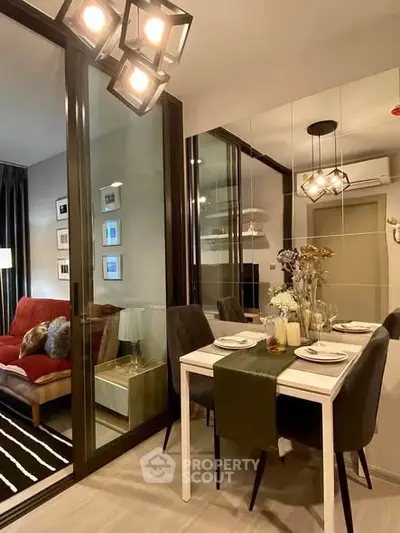 Stylish modern dining area with elegant lighting and mirrored wall, adjacent to cozy living room.