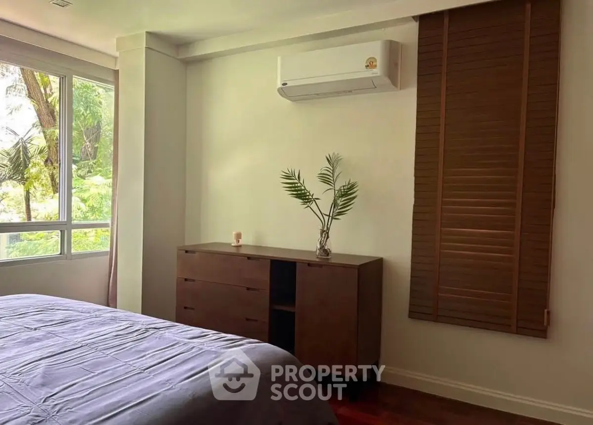 Cozy bedroom with air conditioning and lush garden view, perfect for relaxation.