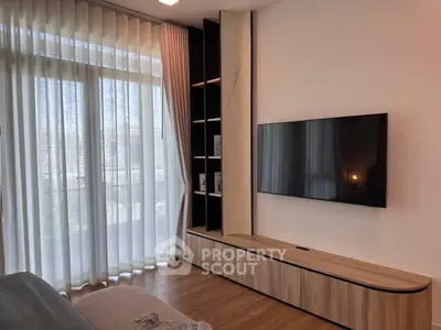 Modern living room with sleek TV setup and elegant floor-to-ceiling curtains.