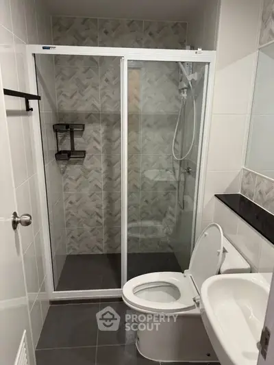 Modern bathroom with glass shower enclosure and sleek fixtures.