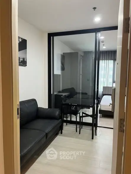 Modern apartment interior with sleek black furniture and glass partition, offering a stylish and cozy living space.