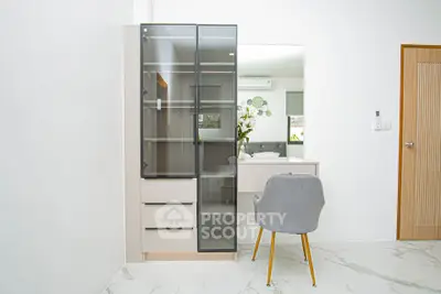 Modern bedroom with sleek glass cabinet and stylish chair