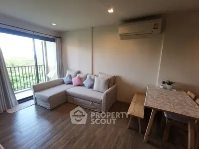 Cozy living room with modern sofa and dining area, featuring a balcony with scenic views.