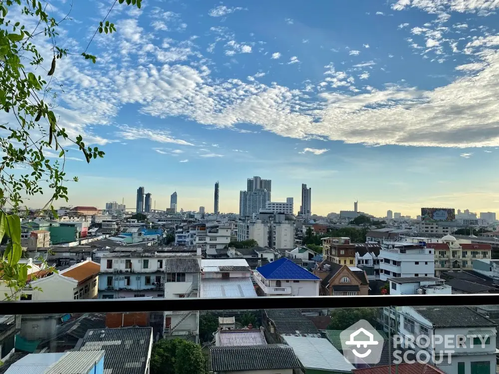 Stunning cityscape view from a high-rise balcony showcasing urban skyline and clear blue sky.