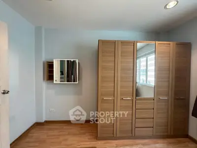 Spacious bedroom with wooden wardrobe and wall-mounted mirror