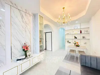 Elegant living room with chandelier, marble accents, and cozy dining area in modern home.
