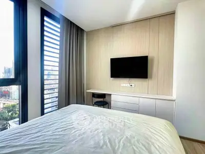 Modern bedroom with city view, featuring sleek design and large windows for natural light.