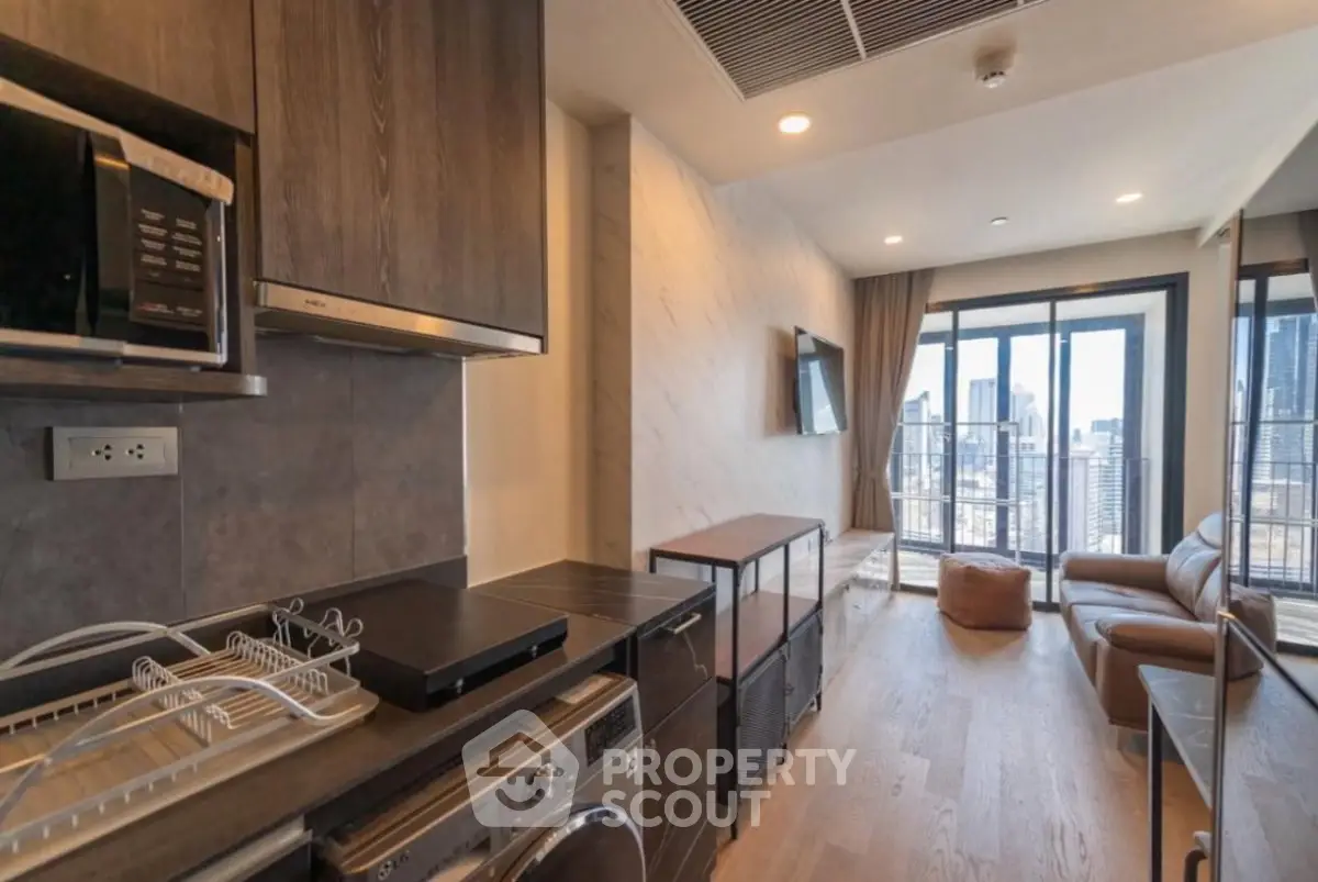Modern open-layout living room with city view, featuring sleek kitchen appliances and stylish decor.