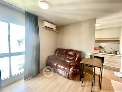 Cozy living room with leather sofa and compact kitchen in modern apartment