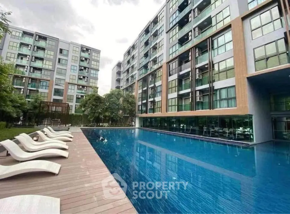 Modern apartment complex with luxurious pool and stylish sun loungers, perfect for relaxation and leisure.