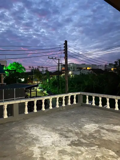 Spacious balcony with stunning sunset view and cityscape backdrop.