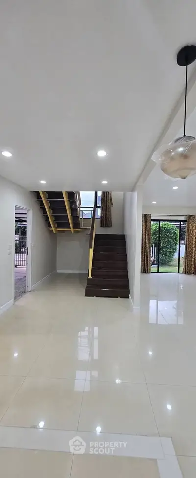 Spacious modern living room with elegant staircase and large windows